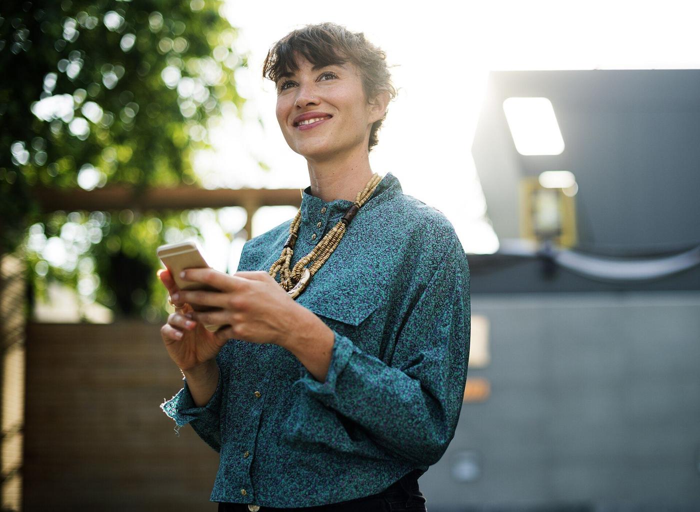 A smiling woman looking at her phone outdoors
